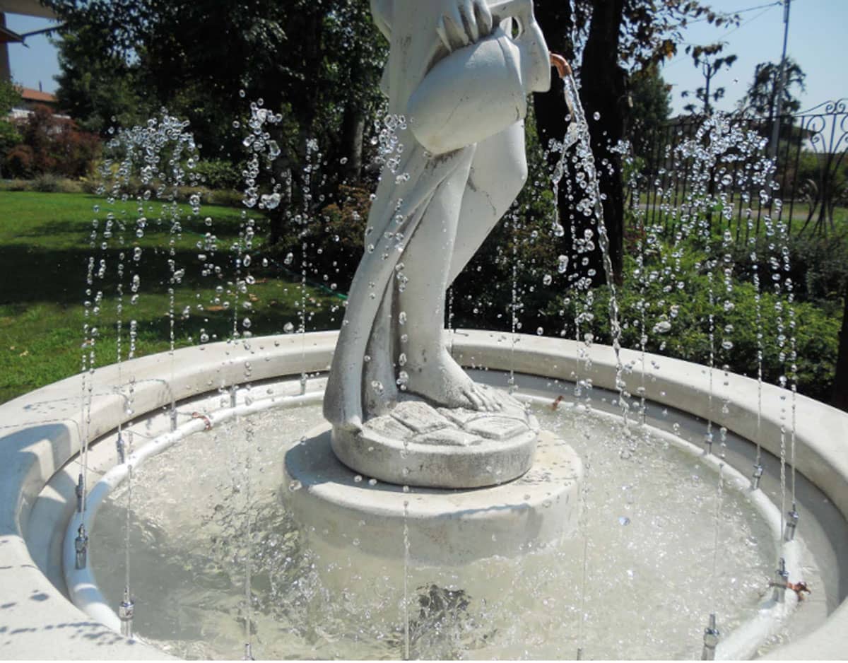 Fontana da giardino con scultura classica e corona di ugelli che creano piccoli getti d'acqua verticali.